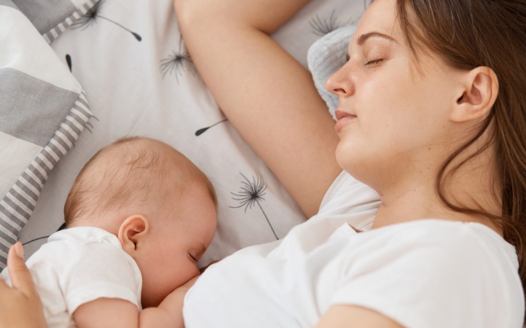 Mother feeding sleepy babies while sleeping in bed